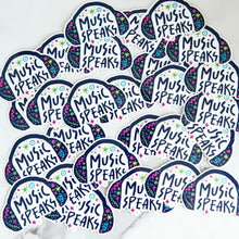 Load image into Gallery viewer, Vinyl die cut stickers with the words &quot;music speaks&quot; with illustrated headphones around the words. 