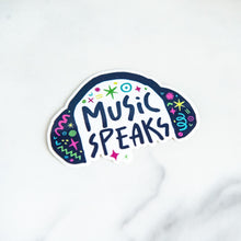 Load image into Gallery viewer, A vinyl die cut sticker with the words &quot;music speaks&quot; with illustrated headphones around the words. 