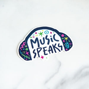 A vinyl die cut sticker with the words "music speaks" with illustrated headphones around the words. 