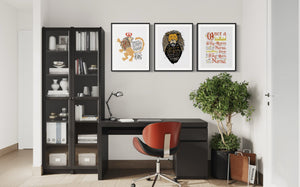 A set of three artwork prints hanging on a wall above a desk of a home office. The artwork is inspired by the Chronicles of Narnia. The first print reads "Course He Isn't Safe, But He's Good. He's the King." The second print reads "At The Sound of Your Roar, Sorrows Will Be No More," and the last print reads "Once a king or queen of Narnia, always a king or queen of Narnia."