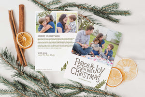 A photo of a double-sided Christmas card showing the front and back of the card laying on a white surface. Around the two sides of the card are pine needles, cinnamon sticks and dried oranges. The front of the card features a photo on the top portion and the words “Peace & Joy to You This Christmas” with space to put your family name below. The back side of the card features two photos with space to write a yearly update. 
