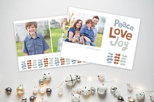A photo of a Christmas card showing the front and back of the card laying on a white surface. To the bottom of the cards are silver and white small ornaments. The front of the card features a photo on the left side with the words “Peace Love Joy” with modern illustrated leaves below. The back of the card features two photos with the modern illustrated leaves. 