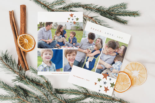 A photo of a double-sided Christmas card showing the front and back of the card laying on a white surface. Around the two sides of the card are pine needles, cinnamon sticks and dried oranges. The front of the card features two photos with the words “Peace. Love. Joy.” above the photos. Below the photos are colored stars and a place where you can put your family name. The back of the card features three photos and colored stars. 