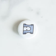 Load image into Gallery viewer, A button pin on a white tabletop. The button features an illustration of a pencil sharpener. 