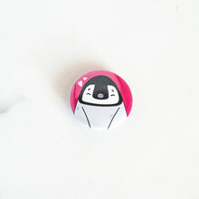 Load image into Gallery viewer, A button pin on a white tabletop. The button design features an illustrated penguin. 