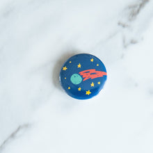 Load image into Gallery viewer, A button on a white tabletop. The button features space-themed illustration of planet. 