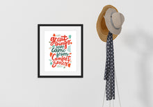Load image into Gallery viewer, A black frame hanging on a wall with a coat rack next to it. The artwork features hand drawn lettering with the phrase &quot;Great things never come from comfort zones.&quot;