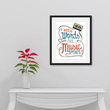 Load image into Gallery viewer, Artwork is featured in a black frame on a white wall. The art is hanging above a white hallway table with a black on top of it. The artwork features hand drawn lettering with the phrase &quot;When words fail, music speaks.&quot; In the upper corner of the words an illustrated cassette tape is featured.