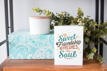 Load image into Gallery viewer, A white greeting card sitting on a a table top with a gift and greenery behind it. The card has the words &quot;A Sweet Friendship Refreshes the Soul.&quot;