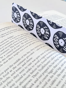 A bookmarks placed inside a book. The bookmark features the words "good vibes" inside an illustrated vinyl record.