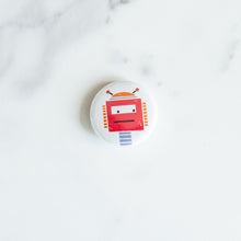 Load image into Gallery viewer, A button pin on a white tabletop. The button features an illustration of a red robot.