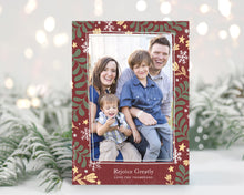 Load image into Gallery viewer, A photo of a one-sided Christmas card showing the front of the card standing up with pine needles behind and blurred white Christmas lights. The photo card features one photo with a frame of illustrated leaves in various colors. Below the photo it reads “Rejoice Greatly” and has space to put your family name. 