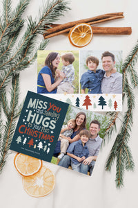 A photo of a double-sided Christmas card showing the front and back of the card laying on a white surface. Around the two sides of the card are pine needles, cinnamon sticks and dried oranges. The front of the card features a photo on the right side and on the left side are the words “ Miss you and sending hugs to you this Christmas” with illustrated trees below the words. The back of the card features two photos with illustrated trees at the bottom.