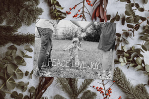 A photo of a one-sided Christmas photo card showing the front of the card. The photo card is laying on top of a white surface covered in pine needles, eucalyptus leaves, and branches with red berries. The card features a photo with the words “Peace Love Joy” over the photo and a space to put your family name below. There are illustrated modern trees on the bottom. 