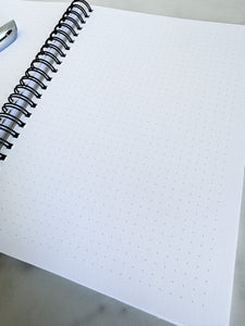 An image showing the notebook opened to show the inside pages. A pen is laying on the notebook. 