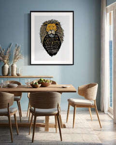 Artwork in a black frame with the with a white matte. The frame is on a wall above a dining table. The artwork features an illustrated Aslan (the lion from Chronicles of Narnia). Inside the lion the Narnia quote is featured reading “At The Sound of Your Roar, Sorrows Will Be No More.”