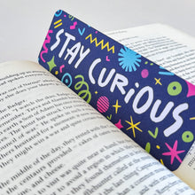 Load image into Gallery viewer, A close up of a bookmark featuring the words &quot;stay curious&quot; with fun whimsical illustrations around it. 