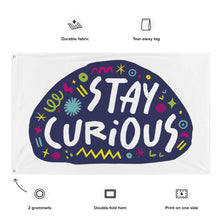 Load image into Gallery viewer, A large flag featured on a white background. The white flag features the words &quot;stay curious&quot; featured inside a a purple shape with sketchy illustrations around. Details of the flag are noted around the image reading &quot;durable fabric, tear-away tag, 2 grommets, double-fold hem, print on one side.&quot;