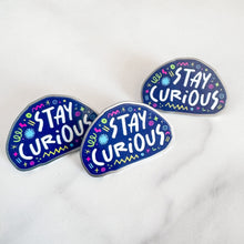 Load image into Gallery viewer, Three enamel pins with the words &quot;stay curious&quot; surrounded by whimsical sketches. 