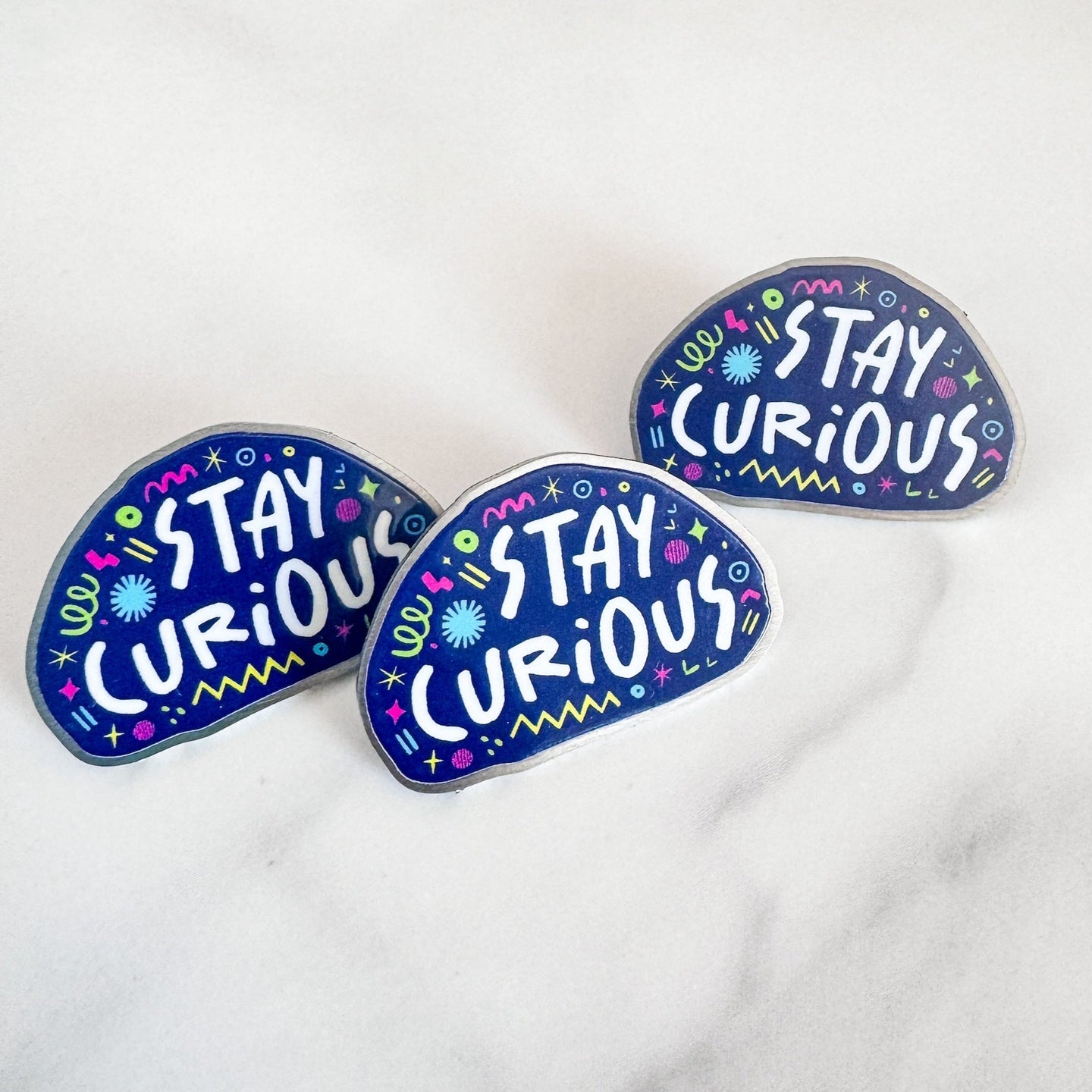 Three enamel pins with the words 