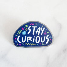 Load image into Gallery viewer, An enamel pin with the words &quot;stay curious&quot; surrounded by whimsical sketches. 