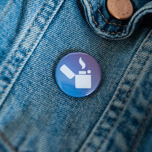 A badge on a jean jacket with a blue background and a lighter illustration in white. 