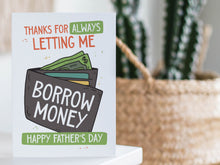 Load image into Gallery viewer, A greeting card is featured on a desktop with a green plant to the side. The card features the words &quot;Thanks for Always Letting Me Borrow Money, Happy Father’s Day.” 