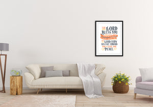 Artwork is featured on the wall of a living room above a white modern sofa. The artwork features hand drawn lettering of the Bible verse Numbers 6:24-26 reading "The Lord bless you and keep you. The Lord make his face to shine on you and be gracious to you. The Lord turn his face toward you and give you peace."