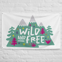 Load image into Gallery viewer, A large white flag featured on a white brick wall. The white flag features the words &#39;wild and free&#39; inside illustrated mountains with sketch trees and other elements around.