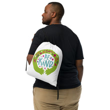 Load image into Gallery viewer, A man with a white drawstring bag on his back. The drawstring bag has the words &quot;Be Kind&quot; with green illustrated hands hugging the design with sketchy illustrations. 