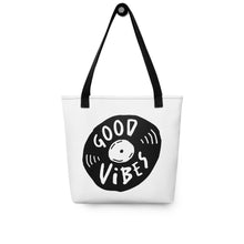 Load image into Gallery viewer, A white tote bag with black handles on a white background. The bag features a design with the words &#39;good vibes&#39; inside an illustrated vinyl record. 