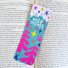 Load image into Gallery viewer, A close up of a bookmark featuring the words &quot;wild and free&quot; featuring illustrated snow capped mountains and trees. 