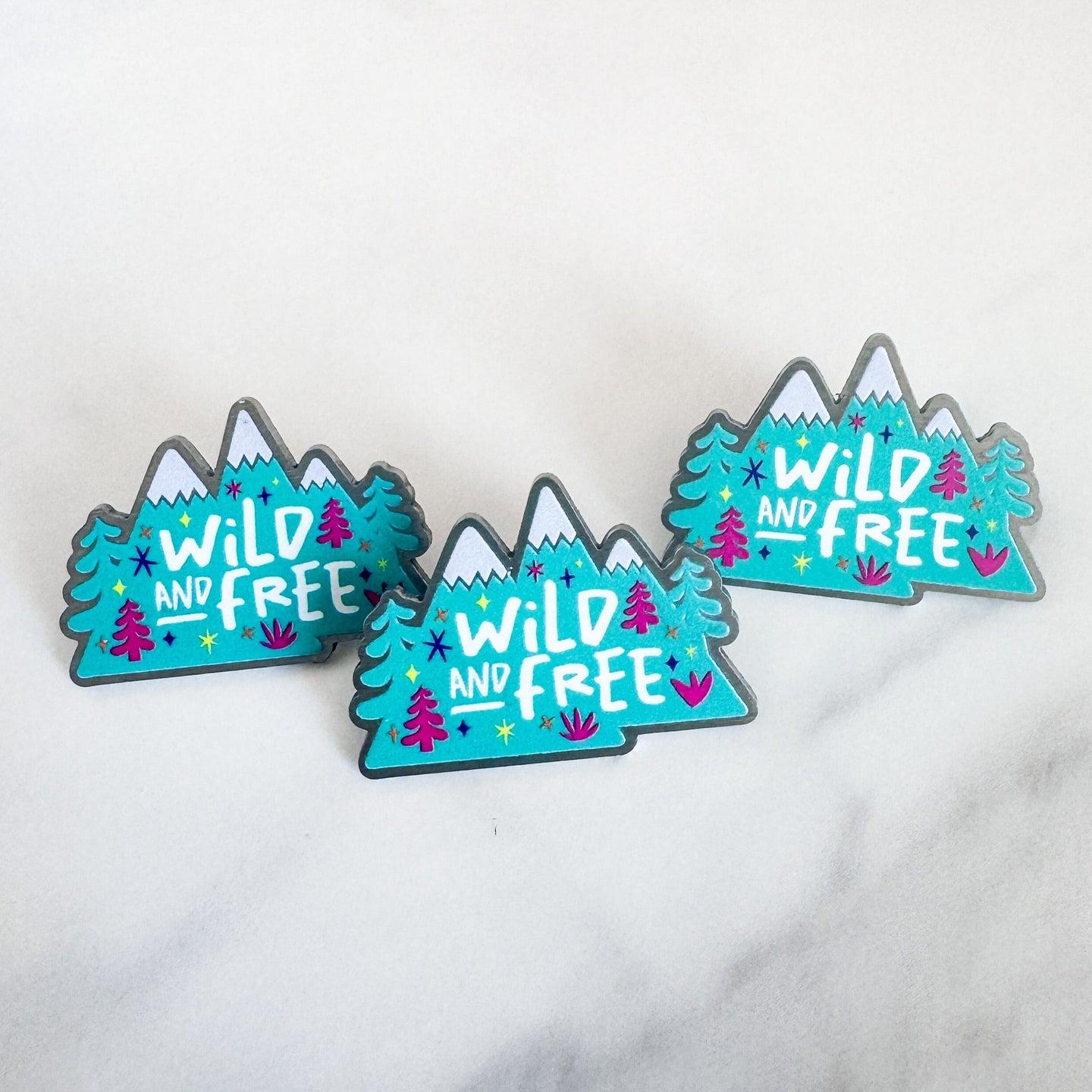 Three enamel pins featuring the words 