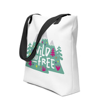 Load image into Gallery viewer, A side view of a white tote bag with black handles on a white background. The tote bag has the design with the words &#39;wild and free&#39; with the words inside illustrated mountains with illustrated trees around the words. 