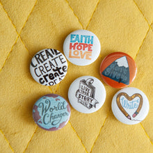 Load image into Gallery viewer, A set of six buttons on a yellow background. The buttons feature word art illustrations with the words &quot;Live Your Story,&quot; &quot;Don&#39;t Give Up,&quot; &quot;Faith Hope Love,&quot; &quot;Create,&quot; &quot;Write,&quot; and &quot;World Changer.&quot;