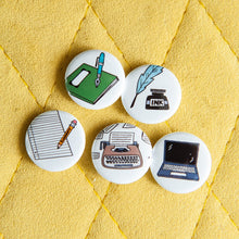 Load image into Gallery viewer, A set of five buttons on a yellow background. The buttons feature illustrations of a typewriter, laptop, pencil and paper, quill pen, and notebook.