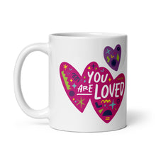 Load image into Gallery viewer, A white ceramic mug on a white background. The mug features a design with the words &#39;you are so loved&#39; inside two illustrated pink hearts with a purple heart above it. 