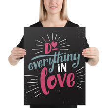 Load image into Gallery viewer, A smiling woman holds up a black art canvas. The canvas reads &quot;Do everything in love&quot; in bright pink and blue hand-lettering style, with white dashes around the words.