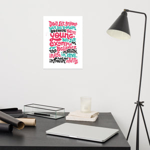 A white print featured on a wall above a desk. The print reads "Don't let anyone put you down because you are young, but set an example for the believers, in speech, in life, in love, in faith and in purity." The lettering is in red, blue and black. 