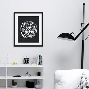 Artwork featured on a wall in a black frame by a shelving unit. The artwork is on a black background with some white texture to give a vintage look. The text is in white and reads “Live a life worthy of the calling you have received.” 