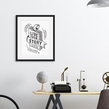 Load image into Gallery viewer, A black frame above a desk with artwork printed on white paper. The artwork features hand drawn lettering with the words &quot;Live Your Story&quot; inside an illustrated book. 