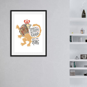 A black from with artwork inside with a white background hanging on the wall. A shelf is off to the right side. The artwork features an illustrated with the words "Course He Isn't Safe, But He's Good. He's the King."