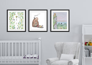 Three black frames featured in a nursery room on a wall above a crib and armchair. The first frame features illustrated artwork with Lucy walking to the lamp. The second frame features an illustration of the beavers house shaped like a beaver with the four children walking up to it. The third frames features a scene on a mountain top with Aslan and Peter overlooking Narnia.  