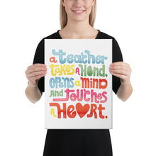 Load image into Gallery viewer, A woman holding a canvas in her hands with the words “A teacher takes a hand, opens a mind, and touches a heart” on the canvas. The “a” in the word “heart” is a heart shape and the words are blue, red, yellow and green. 