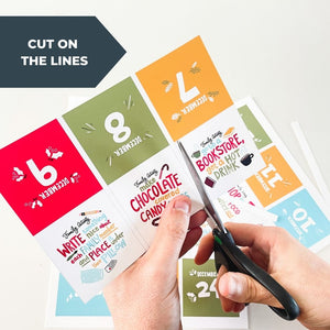An image of hands cutting the Advent calendar cards. The words "cut on the lines" are over the image.