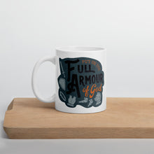 Load image into Gallery viewer, A white mug sits on a wooden board against a white backdrop. The mug features the quote &#39;Put on the full armour of God&#39; in black and orange typography, along with illustrated pieces of armour in medieval style against a dark gray background.