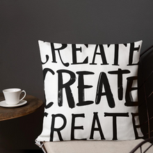 Load image into Gallery viewer, A pillow on a chair with a coffee mug on a table next to it. The white pillow features the phrase “create, create, create&quot; in black lettering with each word in three different fonts. 