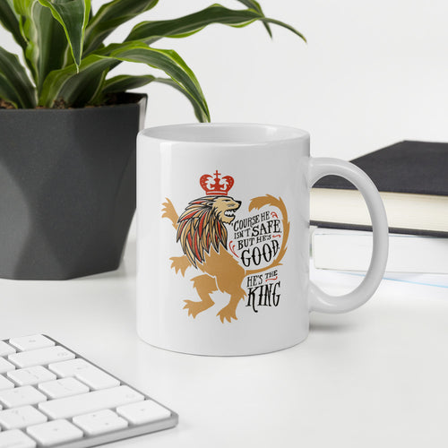 A white coffee mug sitting on an office desk. The mug artwork features hand drawn illustration of the Chronicles of Narnia lion character Aslan. Inside the illustration there is the quote 