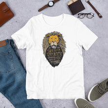Load image into Gallery viewer, A white short sleeved T-shirt laying flat with objects around it. The T-Shirt features hand drawn illustration of the Chronicles of Narnia lion character Aslan. Inside the illustration there is the quote “At The Sound of Your Roar, Sorrows Will Be No More.”