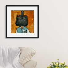 Load image into Gallery viewer, A black frame on a wall featuring an illustration of an Atari controller. The frame is above the corner of a sofa. 